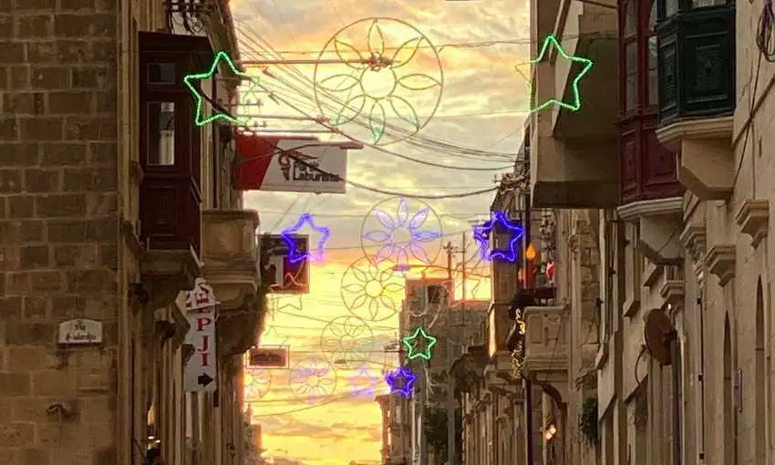 Traditional festive street decorations and lights hanging between balconies in Marsalforn during the village feast season.